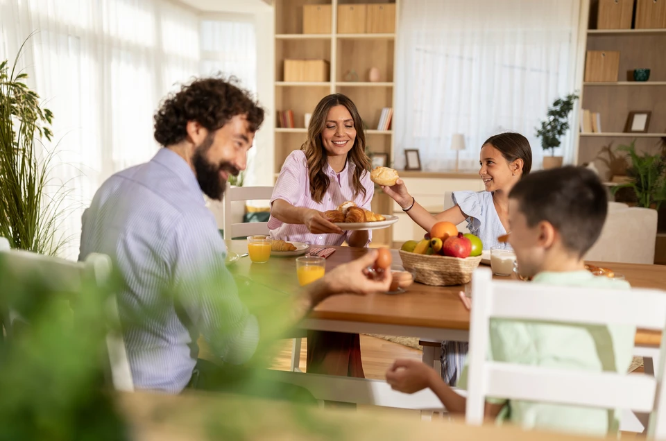 Famille de quatre personnes dans un magasin de meubles, parents et deux enfants testant des matelas et canapés blancs