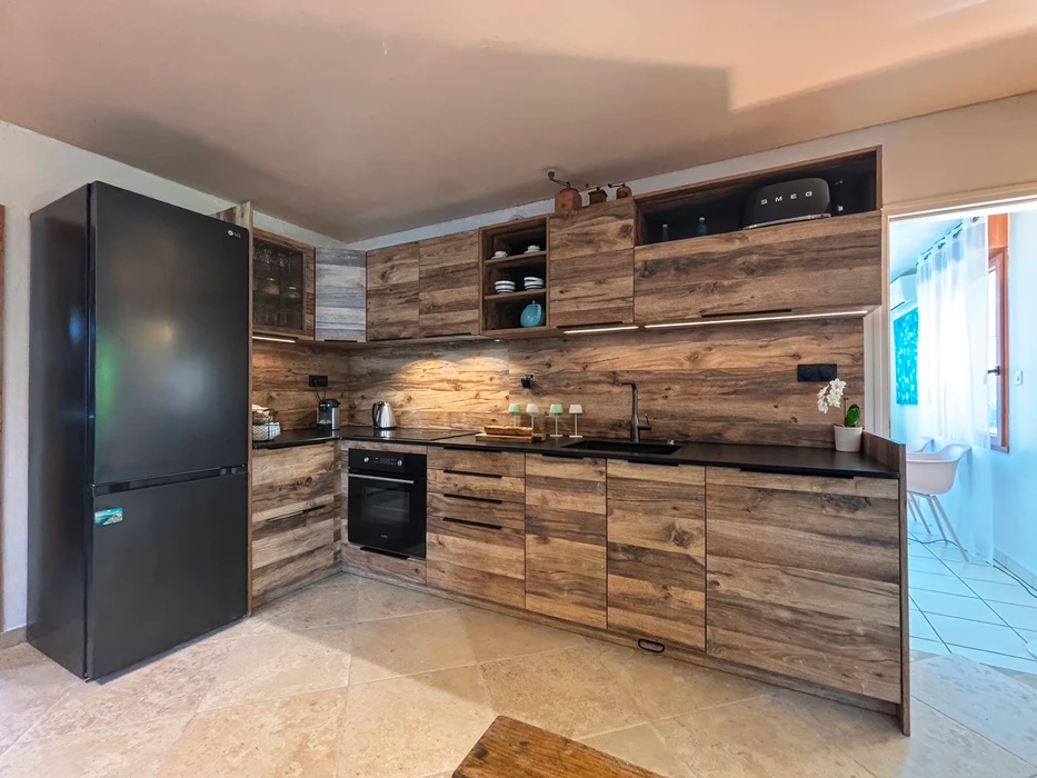 Cuisine moderne en L avec façades bois vieilli effet rustique, plan de travail noir mat, crédence assortie