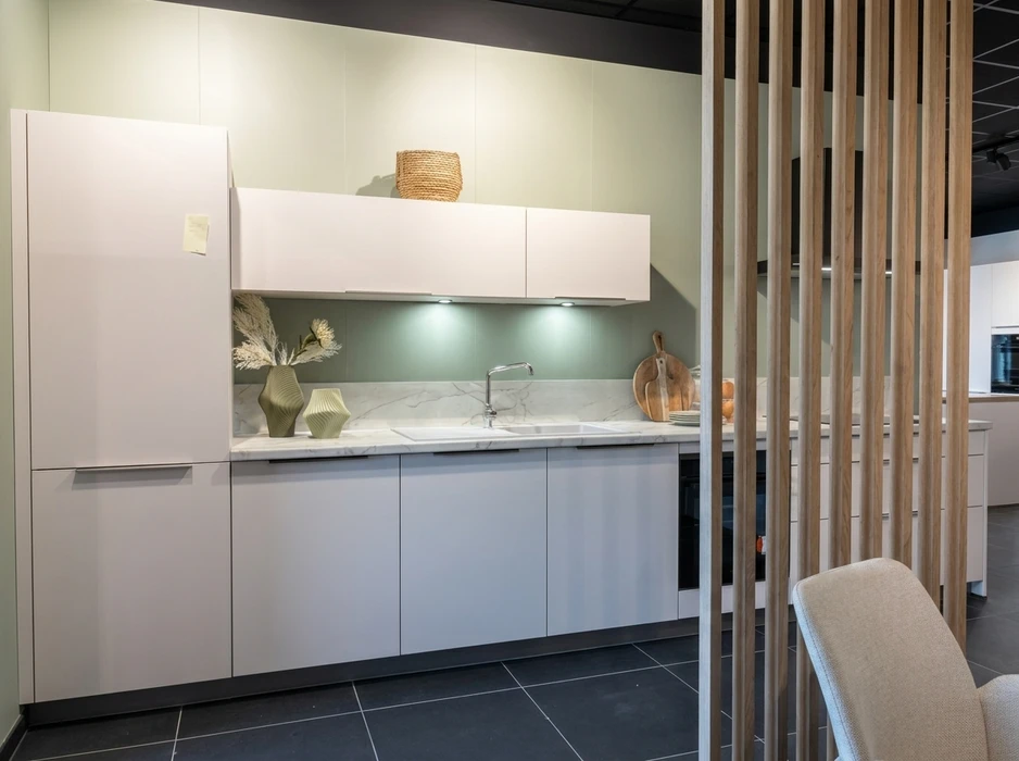 Cuisine moderne rénovée, armoires blanches style shaker, plan de travail en granit beige veiné, îlot central avec évier encastré et lave-vaisselle inox