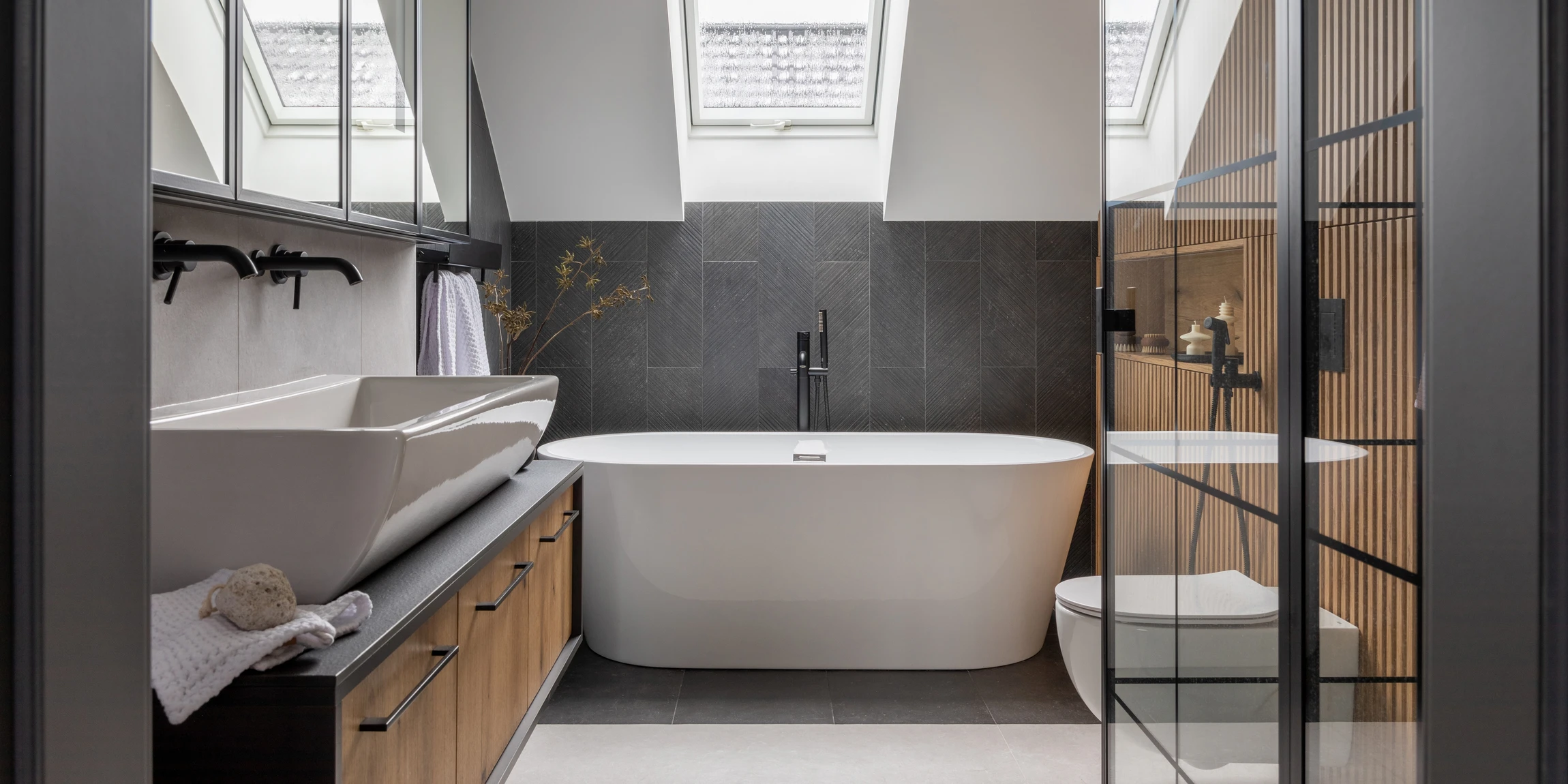 Salle de bain moderne avec vasque à poser blanche sur plan de travail bois, robinetterie chromée contemporaine, miroir rond avec cadre doré